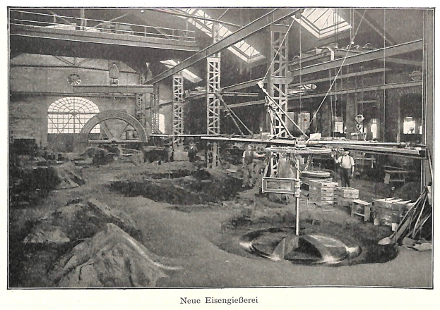Schwarzes und weißes Foto eines Fabrikinneren mit Arbeitern, die Maschinen bedienen, Metallstangen und -pole, beschriftet mit 'Neue Eisenglebeerei, die erste Fabrik in Deutschland' unten.