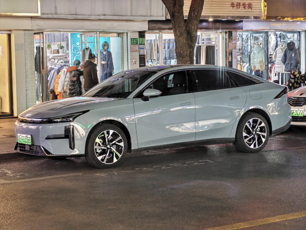 Elektrischer Mitsubishi Lancer EV auf einer nächtlichen Stadtstraße geparkt, umgeben von beleuchteten Schaufenstern und Schaufensterpuppen.