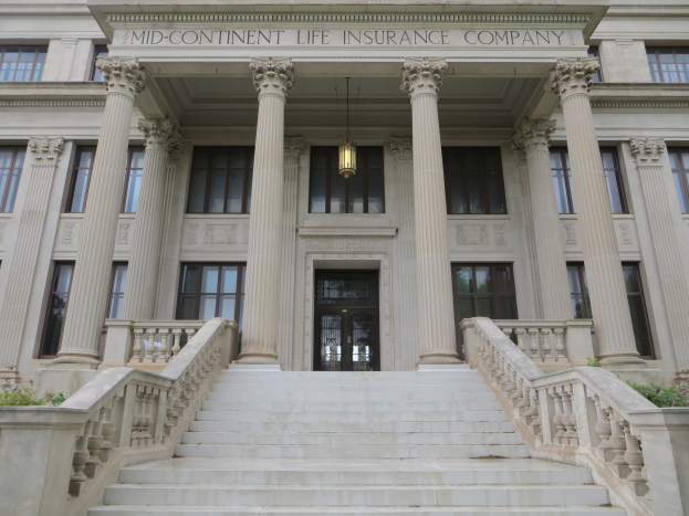 Großes Gebäude mit Fenstern, Säulen, einer Tür, einer Treppe mit Geländern, Pflanzen und einem Schild mit der Aufschrift "Mid-Continental Life Insurance Company".
