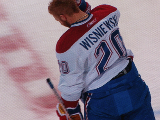 Professioneller Eishockeyspieler in einem "Wisniewski"-Trikot, der auf dem Eis steht und einen Hockey-Schläger hält.