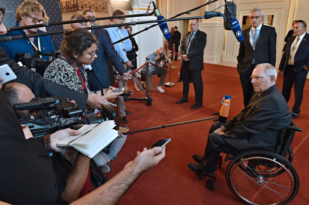 Ein Mann im Rollstuhl ist von Reportern mit Kameras, Mikrofonen und Handys umgeben.