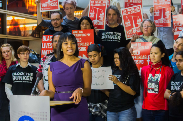 Eine Black-Lives-Matter-Aktivistin spricht in ein Mikrofon zu einer Menge mit Schildern.