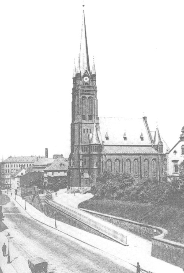 Schwarzes und weißes Foto einer Stadtstraße mit St. Peter's Church im Hintergrund, gesäumt von Gebäuden, Bäumen, Fahrzeugen und einigen Fußgängern.