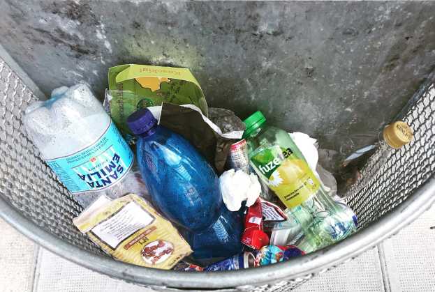 Ein Metallmüllcontainer voller Plastikflaschen, Beutel und andere Gegenstände.
