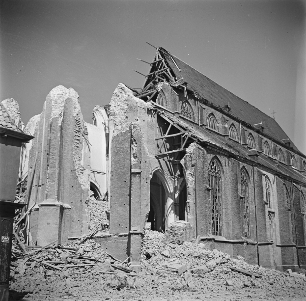Schwarzes und weißes Foto einer zerbombten alten Kirche mit zerbrochenen Wänden und verstreuten Trümmern, der Himmel ist oben sichtbar.