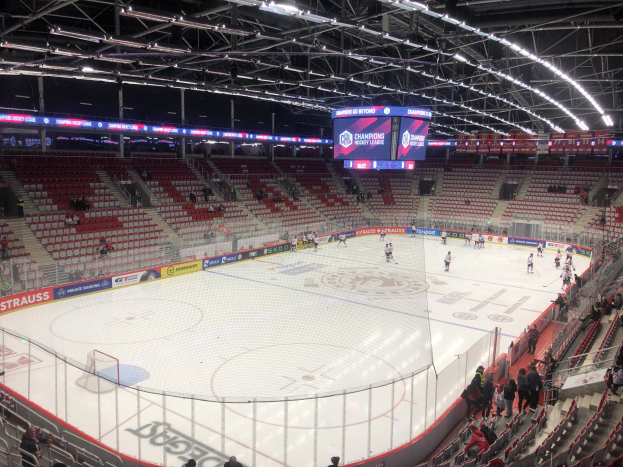 Ein Eishockeyspiel in einer großen Arena mit Zuschauern, einem Zaun um die Eisfläche, einem Display mit der Aufschrift "St. Louis Blues vs Detroit Red Wings", Metallrahmen und einer Decke mit Deckenbeleuchtung.