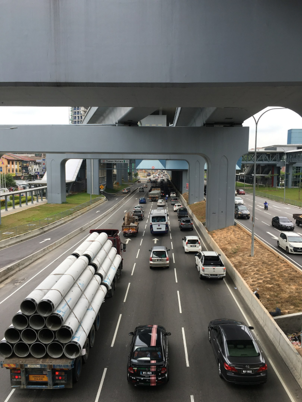 Schwerer Verkehr auf einer Autobahn, die unter einer Brücke verläuft.