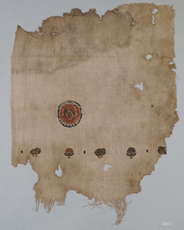 Ein Stück Stoff mit einem kreisförmigen Design, das aus leuchtenden, detailreichen Formen besteht, einschließlich Kreisen, Quadraten und Dreiecken auf einem weißen Hintergrund.