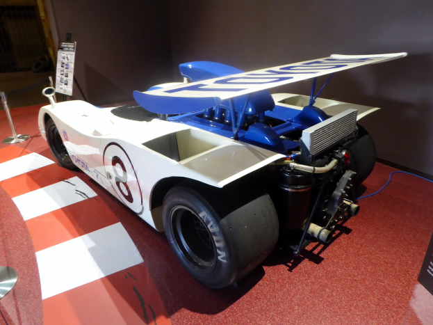 Ein weiß-blaues Rennauto in einem Museums Setting auf der Goodwood Festival of Speed, umgeben von Barrieren und Informationsschildern.