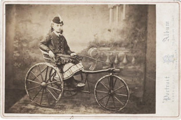 Schwarz-weiß-Foto einer Frau auf einem Fahrrad in einem Kleid und einer Mütze, mit Text auf der rechten Seite.