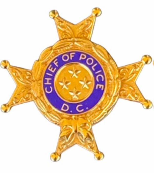 Ein Polizeiabzeichen mit der Aufschrift "Polizeipräsident" auf einem weißen Hintergrund.