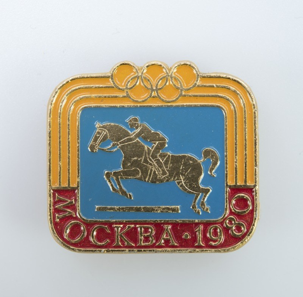 Olympisches Abzeichen der Winterspiele 1988 mit einer Person in weißem Hemd und blauen Shorts, die ein kastanienbraunes Pferd mit weißer Mähne und Schweif gegen einen hellblauen Himmel mit weißen Wolken reitet.