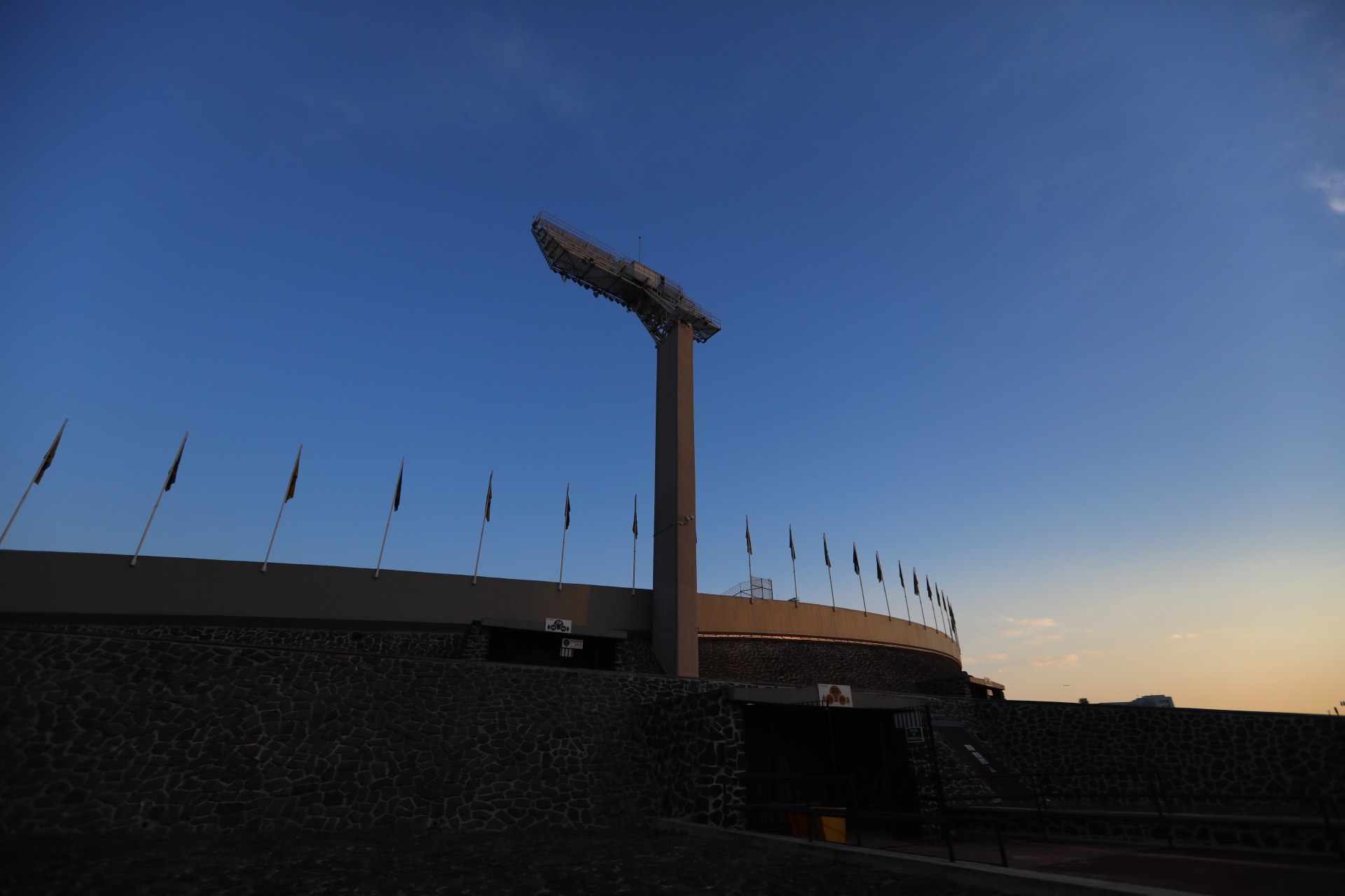 Olympiastadion in Rio de Janeiro, Brasilien, mit zentralem Pfosten, umgebender Wand und einigen Flaggen sowie Himmel oben.