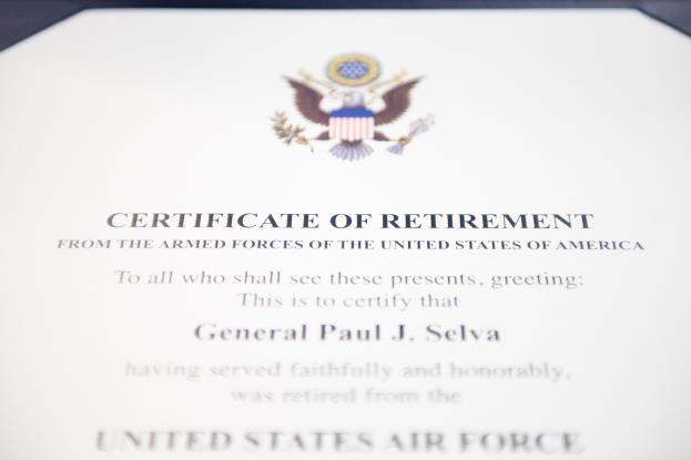 Rahmenurkunde der United States Air Force mit blauem Rand, zentrales Sternschild-Logo umgeben von einem Lorbeerkranz und einem Banner mit der Aufschrift "Ruhestand" in schwarzer Tinte.