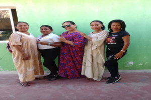 Eine Gruppe von Frauen steht zusammen vor einer grünen Wand mit einem Fenster auf der linken Seite und nimmt an einem International Women's Day-Event teil.