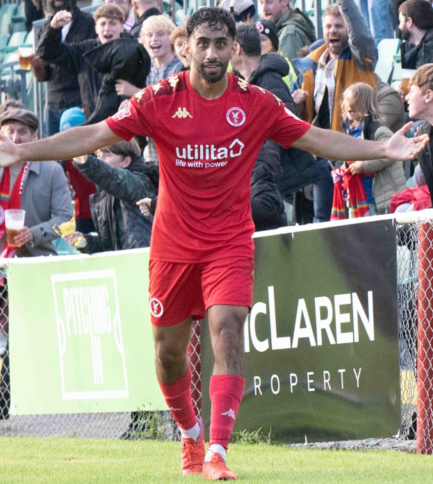 Ein Fußballer in roter Uniform rennt mit ausgestreckten Armen auf einem Feld, umgeben von einer Menge, mit einem "Middlesbrough FC v Swansea City - Sky Bet Championship"-Schild im Hintergrund.