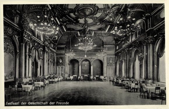 Schwarz-weißes Foto eines großen Raums mit Tischen, Stühlen, Säulen, Bögen und Kronleuchtern, beschriftet mit "Festival der Gesellschaft der Freunde, Berlin" unten.