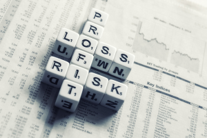 Crossword puzzle with the words "loss, risk, and risk" over a newspaper filled with text and numbers, suggesting financial planning and risk management.