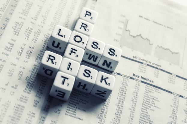 Crossword puzzle with the words "loss, risk, and risk" over a newspaper filled with text and numbers, suggesting financial planning and risk management.
