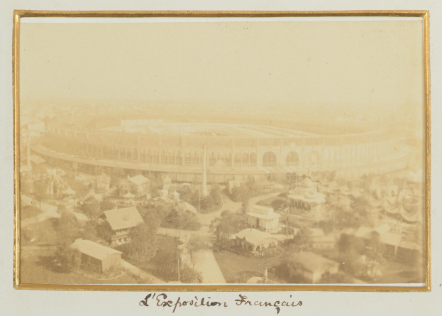 Altes Schwarz-Weiß-Foto eines Stadions, umgeben von Stadtgebäuden, Bäumen und Strommasten mit Text unten.