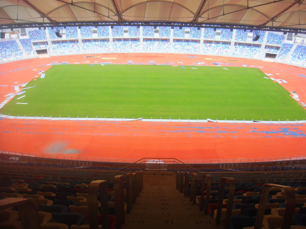 Großes Stadion mit vielen Zuschauern, Featuring Terrassen, Geländer, Treppen und Dach, mit dem Spielfeld in der Mitte sichtbar.
